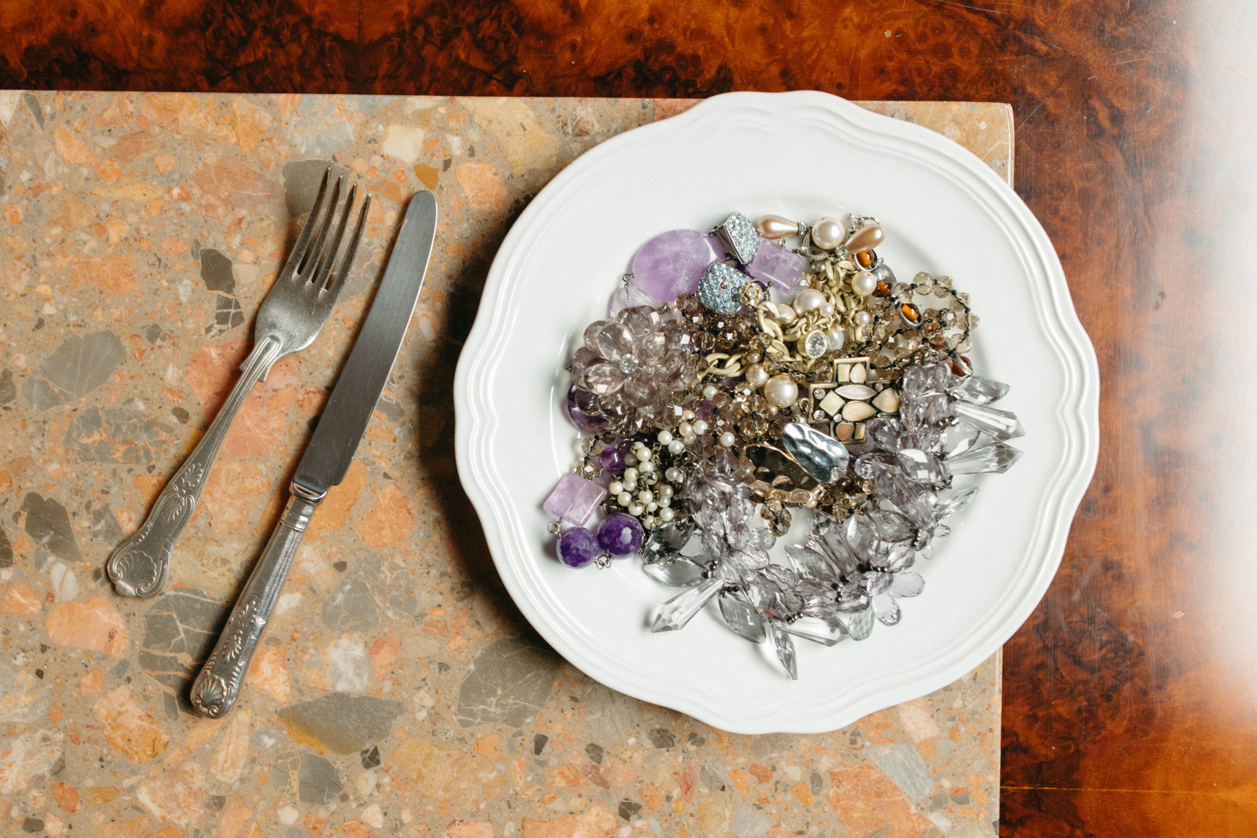 assiette de bijoux mêlant vraies pierres, perles et strass en verre